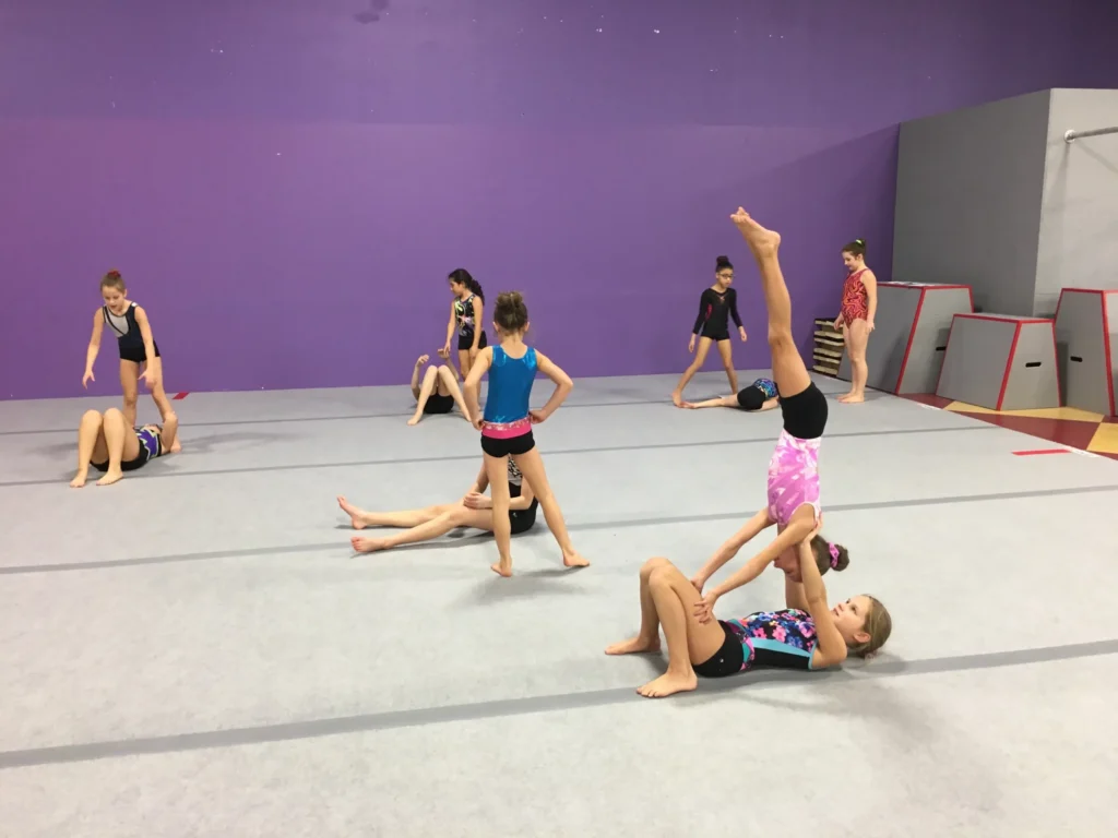 Recreational gymnastics students practising acrobatic skills with a coach
