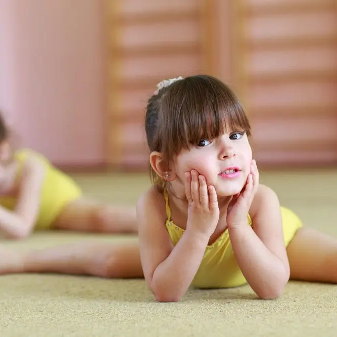 Preschool gymnast holding a split on the floor