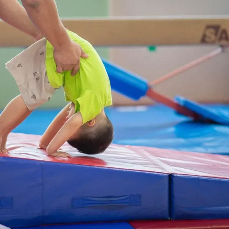 Young child rolling down a wedge mat in a preschool gymnastics class